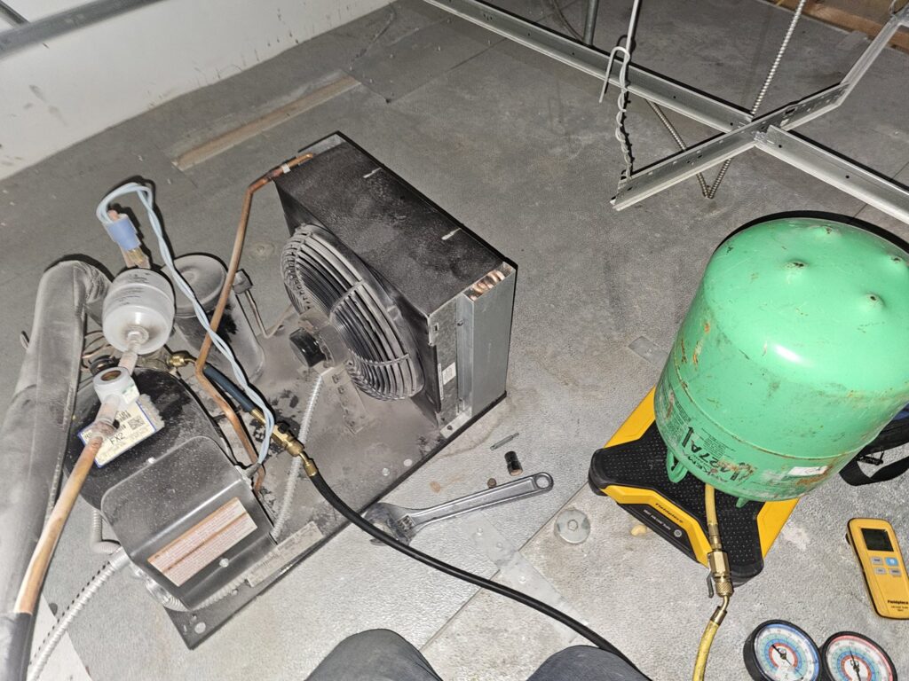 Servicing a refrigeration unit, showing internal components and connected gauges, by Henry Refrigeration & Hvac Utah in Ogden, UT.