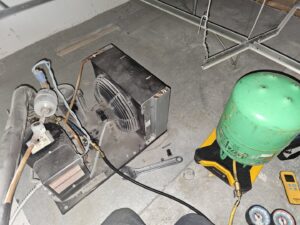 Servicing a refrigeration unit, showing internal components and connected gauges, by Henry Refrigeration & Hvac Utah in Ogden, UT.