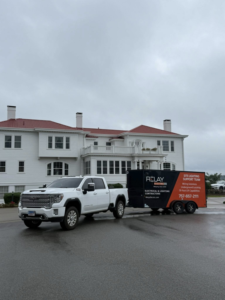 A white pickup truck towing a branded Relay Electric, LLC service trailer in Suffolk, VA, ready for electrical and lighting jobs.