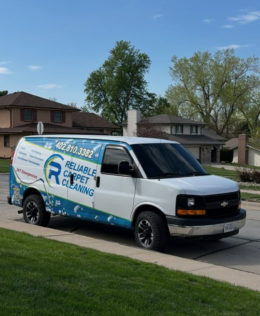 A branded service van for Reliable Carpet Cleaning LLC parked on a residential street in Liverpool, NY.