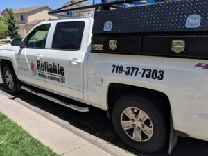 A Reliable Heating & Cooling LLC service truck parked on a residential street in Colorado Springs, CO