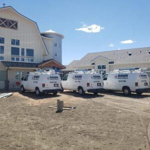 Three Reliable Heating & Cooling LLC service vans parked at a construction job site in Colorado Springs, CO