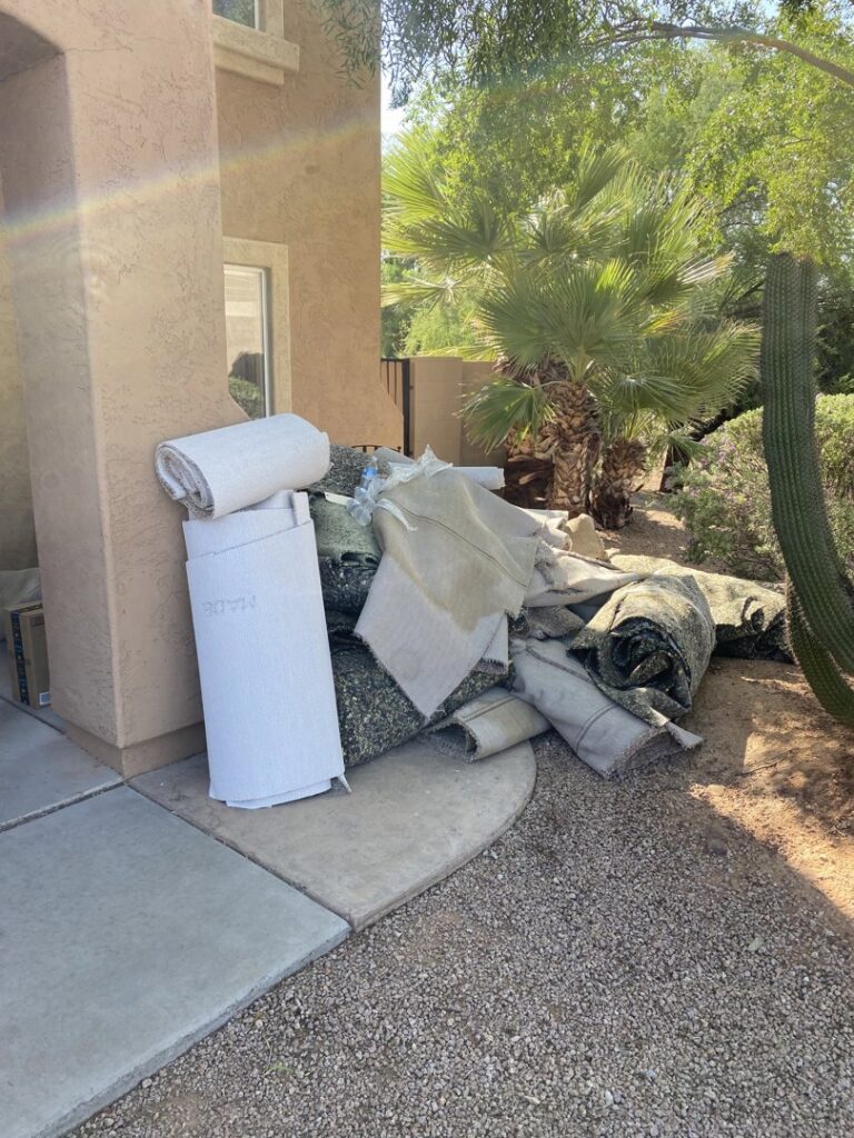 A pile of removed old carpet and padding outside a home by Mark Hart Flooring Consultant at RM Interiors & Design in Mesa, AZ.
