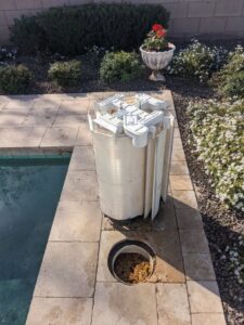 A pool technician removing dirty filter cartridges from a pool filter housing for cleaning by Cruz pool service and repair in Lees Summit, MO