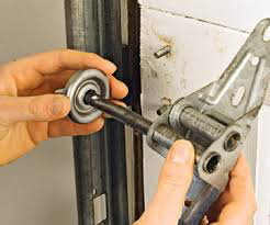 Hands performing a repair on a garage door roller and hinge mechanism by Able Garage Door Service, LLC in Tucson, AZ.