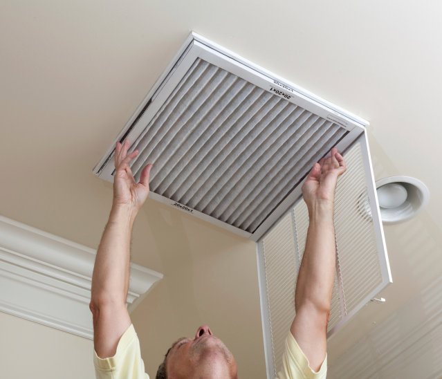 A person replacing an air filter in a ceiling vent, a service by Wright Way Air Duct Cleaning in Streamwood, IL