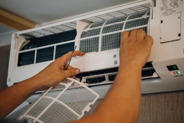 Hands replacing a dirty air filter in an HVAC unit for Controlled Climate Solutions in Decatur, AL.