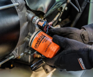 A technician replacing a Generac genuine parts oil filter on a generator during maintenance by Generator Maintenance of Georgia in Atlanta, GA.