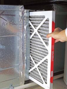 A hand replacing an HVAC air filter, a service provided by Climate Solutions. Inc. in Cape Coral, FL.