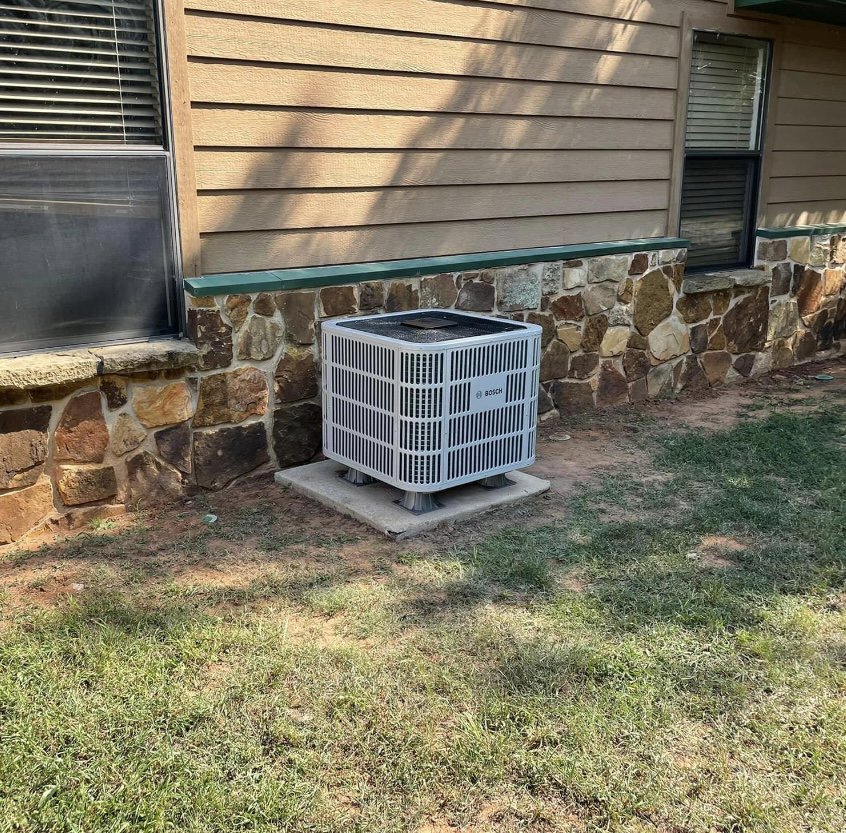 A newly installed residential AC condenser unit by Chapman HVAC outside a home in Cleveland, OK.