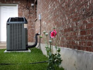 A residential outdoor air conditioning unit next to a brick house, installed by Reliance Home Comfort in Hampton, VA.