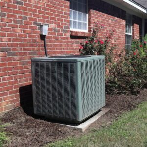 A residential air conditioning unit installed next to a brick house by All The Way Heating & Cooling in Middleburgh, NY