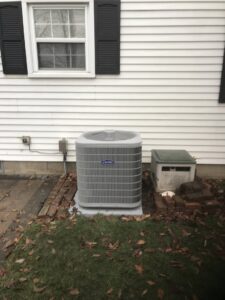 A newly installed outdoor Carrier AC condenser unit next to a white residential house by Chad Byers - Edge Guys Heating & Cooling in Carmel, IN