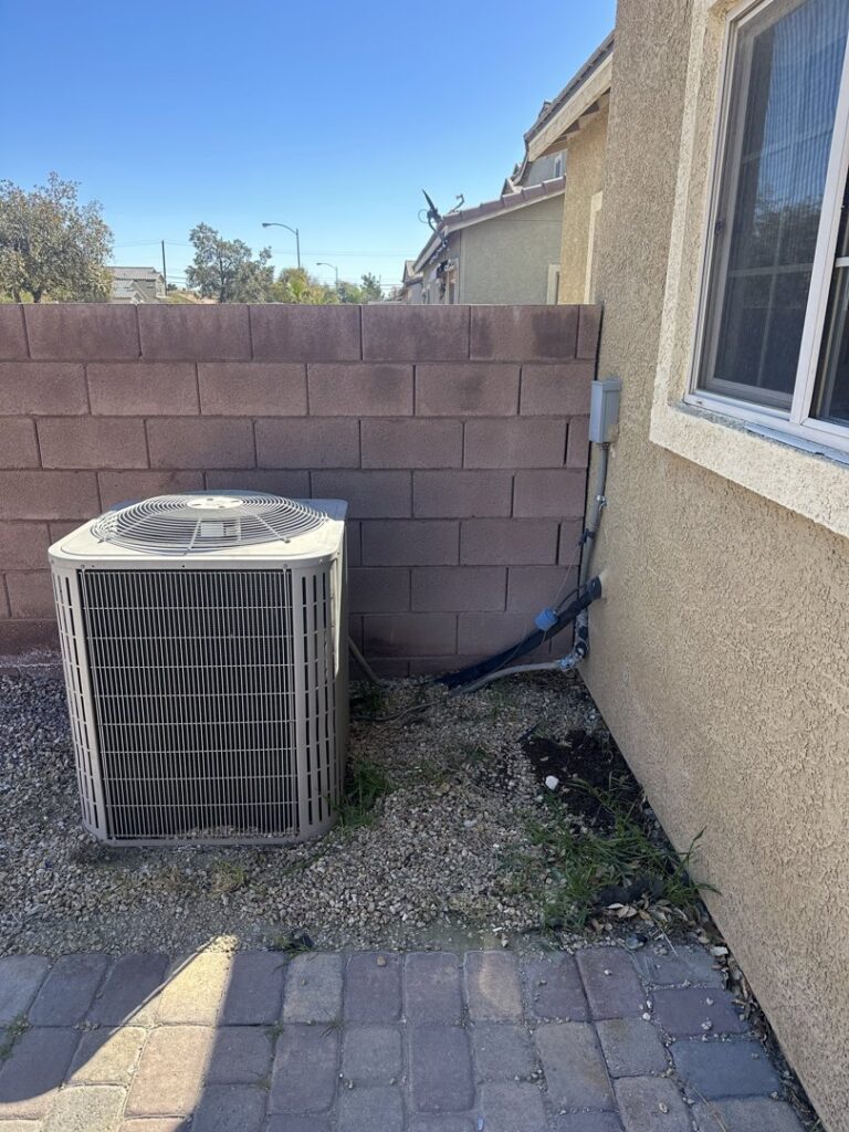 A residential air conditioning unit installed next to a brick wall by Usa Air Conditioning & Heating in Las Vegas, NV