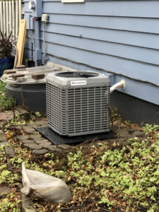 A Champion outdoor AC unit installed on a pad next to an older residential home by Air Care in Sioux Falls, SD.