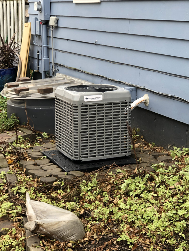 A Champion outdoor AC unit installed on a pad next to an older residential home by Air Care in Sioux Falls, SD.