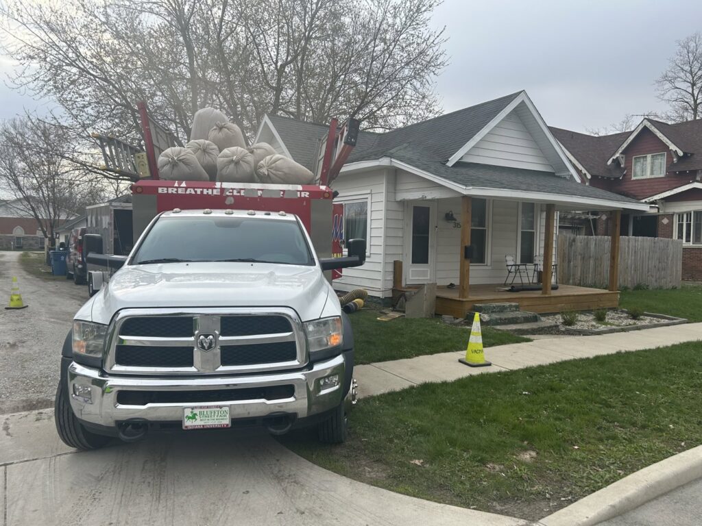 A Vacman Air Duct Cleaning truck with debris bags parked outside a residential home in South Bend, IN