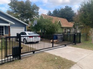 A residential automatic black metal sliding gate installed by Iron Fence Services, LLC in Lancaster, TX.
