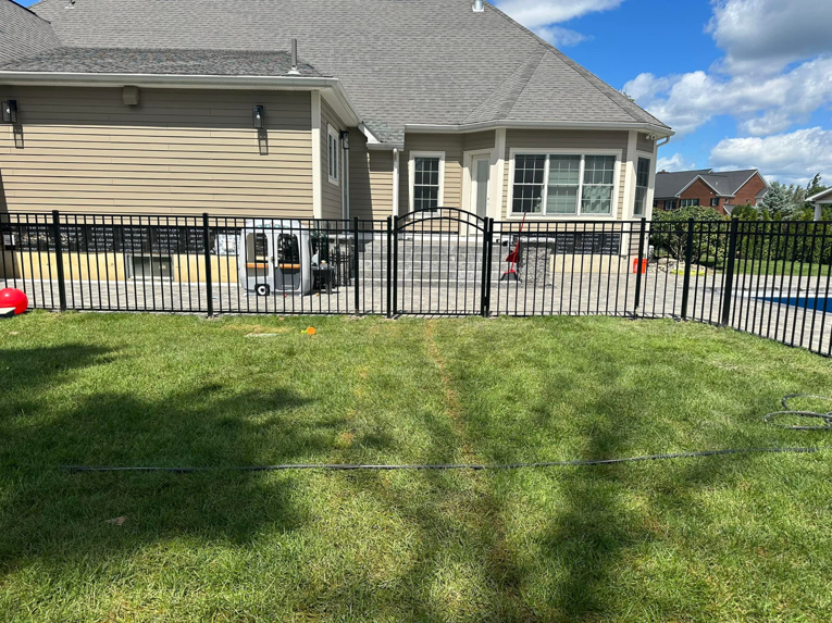 Full view of a residential backyard fence installation with a black metal fence and gate by Fenced Up, LLC in Ravena, NY.