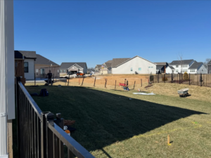 Residential backyard fence installation in progress with posts and workers by BK FenceWorks in Wentzville, MO.
