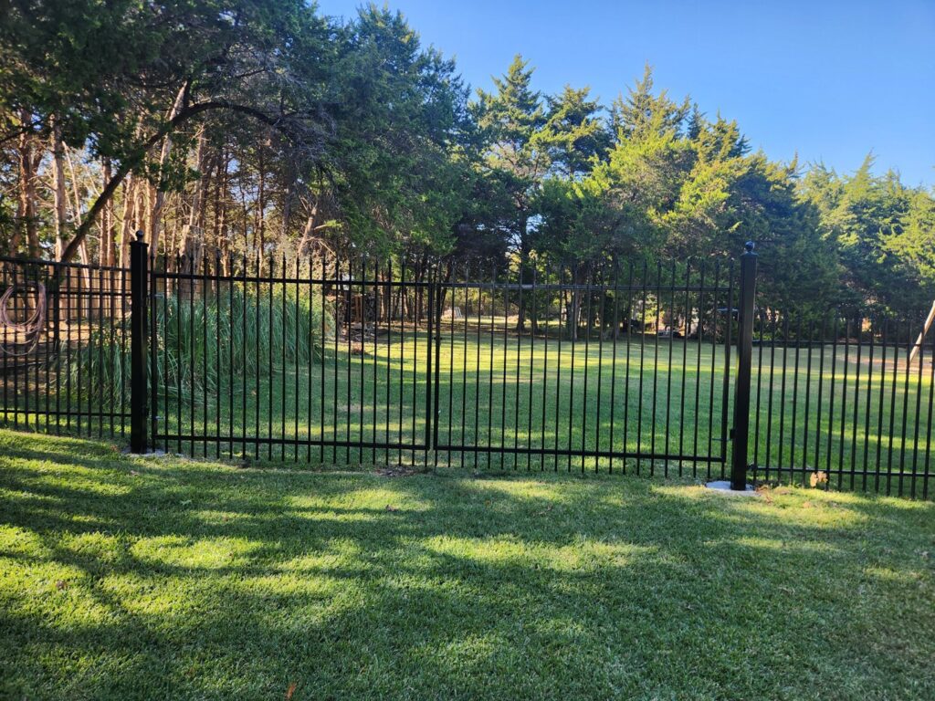 A residential black iron fence installed in a backyard by Iron Fence Services, LLC in Lancaster, TX
