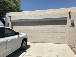 A residential beige garage door on a stucco home, installed or serviced by Johns Garage Doors in Tucson, AZ.