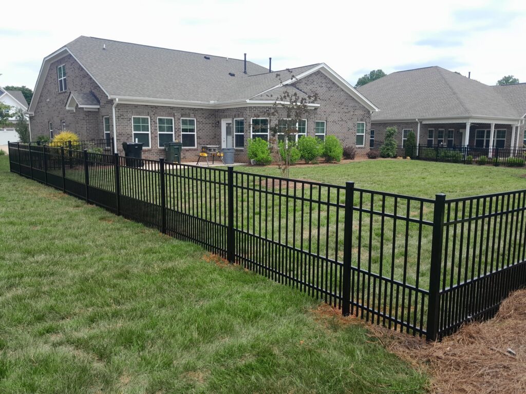A sleek black aluminum fence enclosing a residential backyard, installed by Aguilarfence services LLC in Clayton, NC.