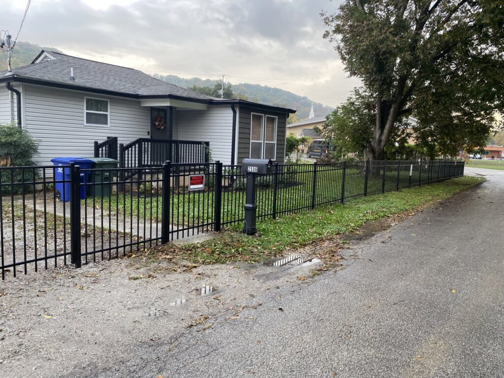 A residential black aluminum fence with a gate installed along a street, completed by Holmes Fence Company in Chattanooga, TN.