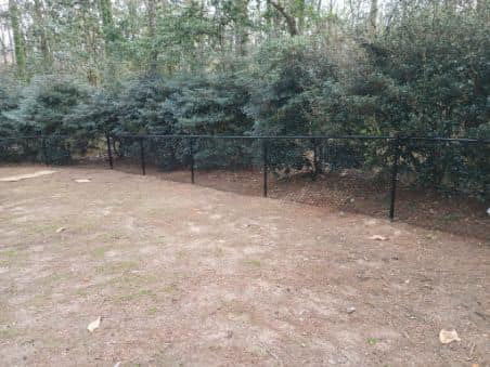 A residential black chain-link fence installed in a backyard by Almaraz & Sons LLC in Macon, GA.