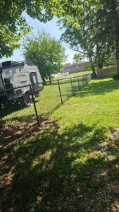 A residential black chain-link fence installed in a backyard by JM Fence Works in Davenport, IA.