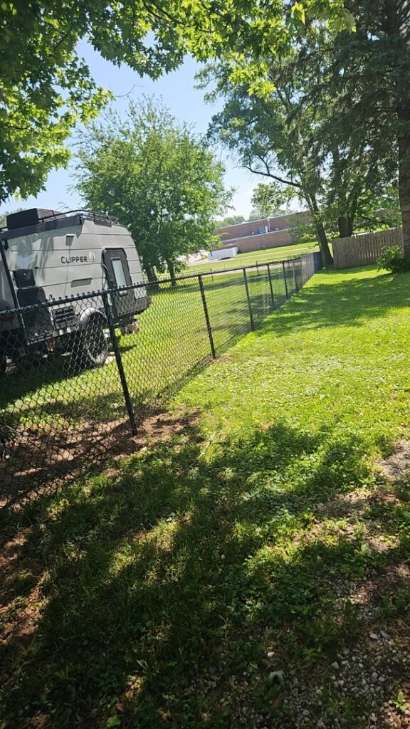 A residential black chain-link fence installed in a backyard by JM Fence Works in Davenport, IA.