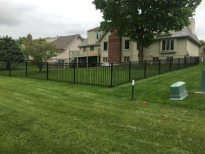 A black metal fence installed in a residential backyard by Mann Fence Co., Inc. in Olathe, KS.