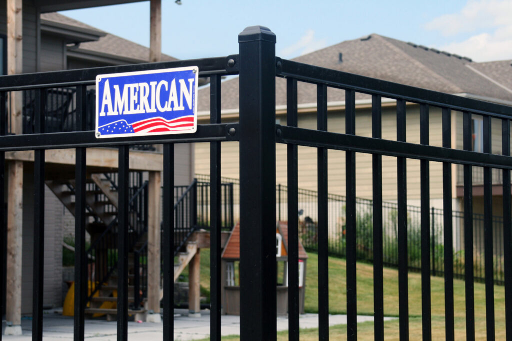 A residential black metal fence with an American Fence Company sign in Grand Island, NE.