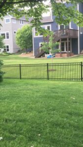 A residential black metal fence in a backyard with a house in the background, installed by Mauer Company in Little Canada, MN.