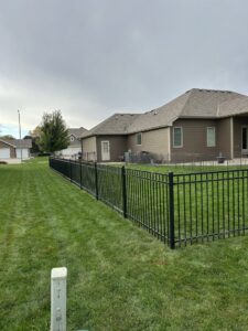 A long black ornamental fence installed in a residential backyard by Bostwick Fencing, LLC in Sioux City, IA.