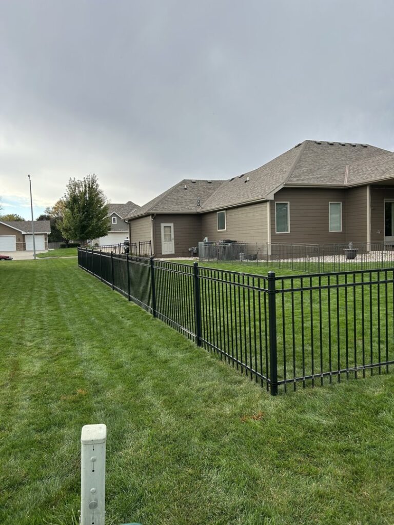 A long black ornamental fence installed in a residential backyard by Bostwick Fencing, LLC in Sioux City, IA.
