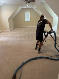 A professional performing residential carpet cleaning, showing distinct cleaning patterns, by Treo General Services of North Carolina LLC in Durham, NC.