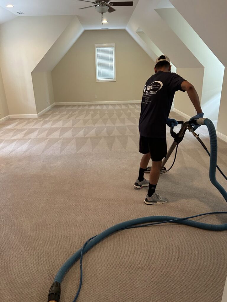 A professional performing residential carpet cleaning, showing distinct cleaning patterns, by Treo General Services of North Carolina LLC in Durham, NC.