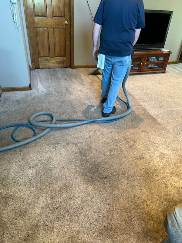 A technician performing residential carpet cleaning service in a living room by Hopman Rug Cleaners in Hammond, IN.