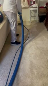 A professional performing residential carpet cleaning with a wand tool by Word of Mouth Cleaning Services in Houston, TX.