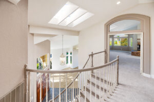A residential staircase and hallway featuring new light-colored carpet installed by Floor & More in San Marcos, CA.