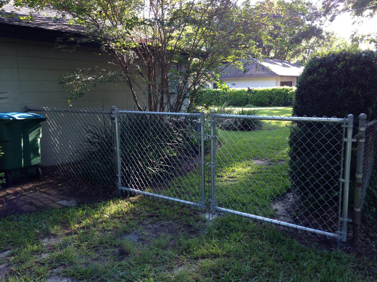 A durable chain-link fence with a gate installed in a residential backyard by Hernandez Fence in Orlando, FL.