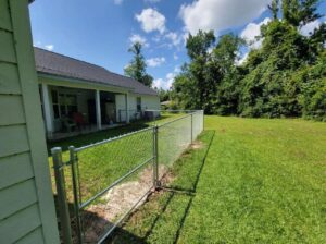 A residential chain-link fence with a gate providing security for a backyard by JH Fencing in Lawrence, KS.