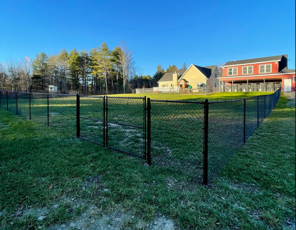 A black chain-link fence with a double gate enclosing a residential backyard, a project by Vision One Construction LLC in Schenectady, NY