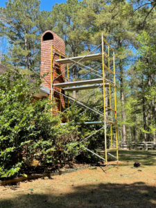 Residential brick chimney with scaffolding for a chimney sweep job by Louisiana Chimney Services in Shreveport, LA.