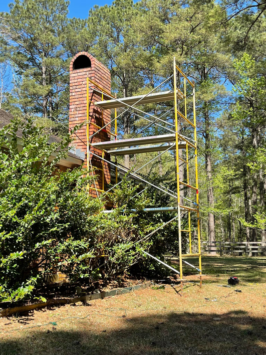 Residential brick chimney with scaffolding for a chimney sweep job by Louisiana Chimney Services in Shreveport, LA.