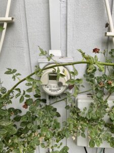 A residential electric meter mounted on the exterior wall of a house, a common service point for AA Electric Contractors in Chicago, IL.