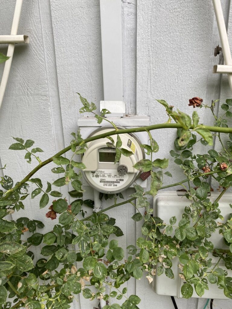 A residential electric meter mounted on the exterior wall of a house, a common service point for AA Electric Contractors in Chicago, IL.