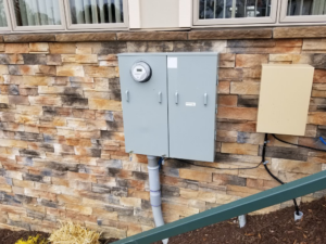 A residential electric meter and panel installed on a stone wall by Cargo Electric LLC in Philippi, WV