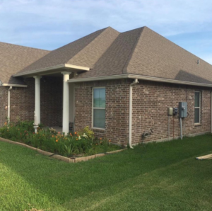 An exterior view of a residential electrical meter and conduit on a brick house, serviced by Immaculate Electric in Lake Charles, LA.